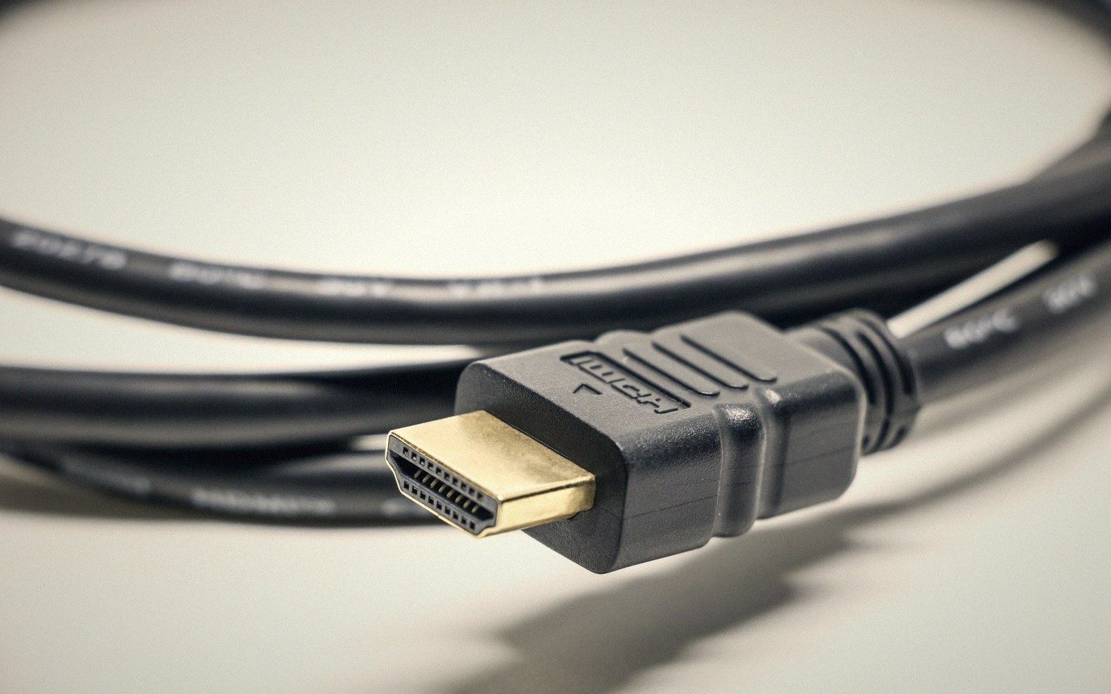 Coiled HDMI cable with gold-plated connector resting on a light surface