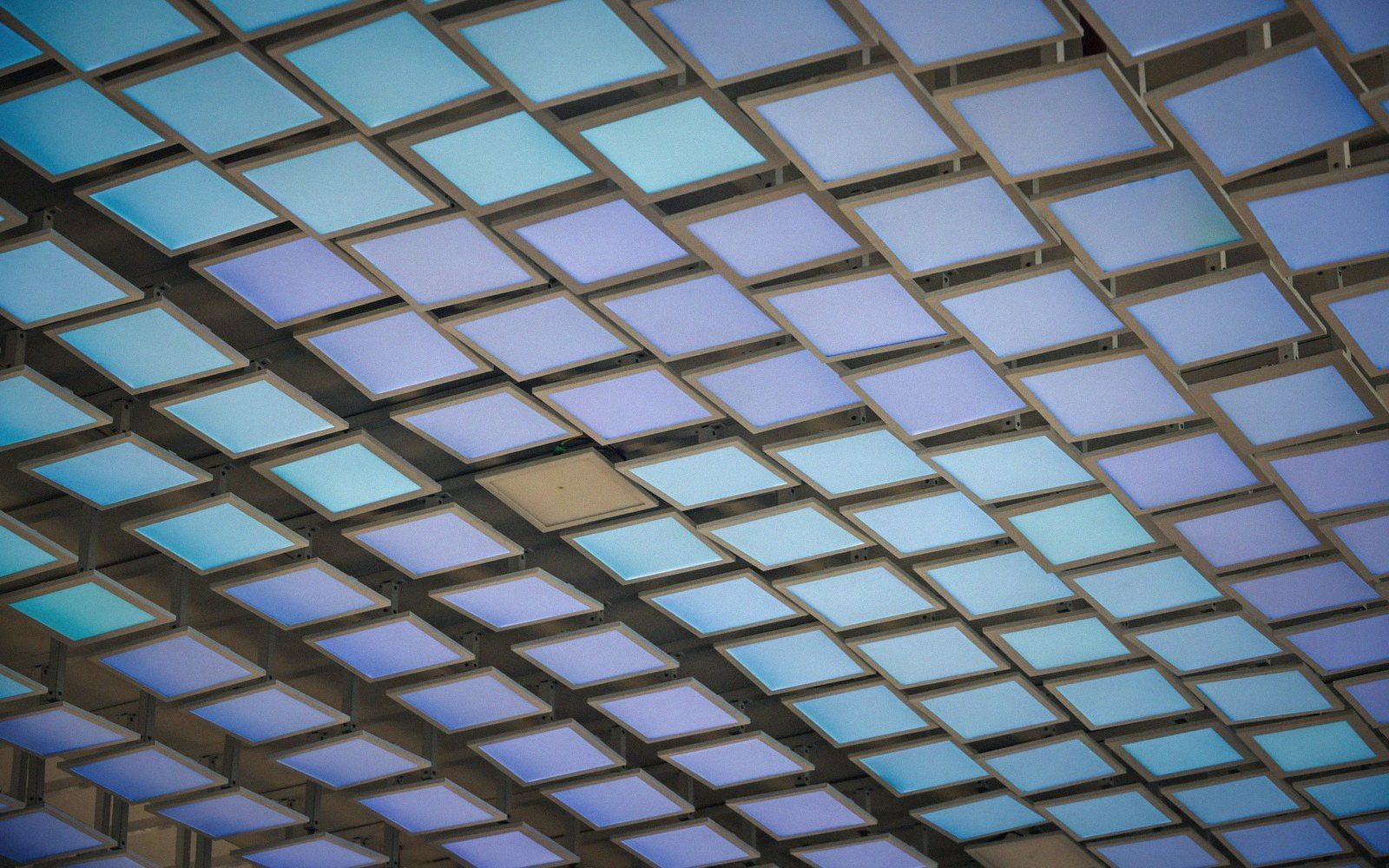 Grid of illuminated blue and purple square panels forming a repeating ceiling pattern