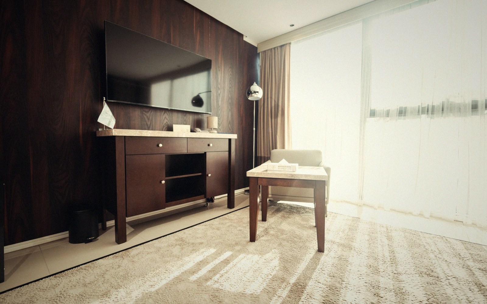 Wall-mounted flat-screen tv above a dark wood console with a small desk and chair nearby