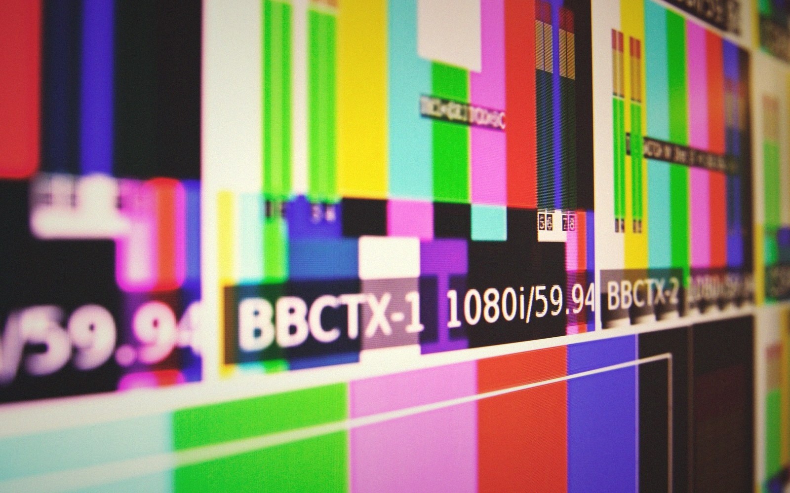 Color bars test pattern on a monitor showing broadcast signal labels and resolution data