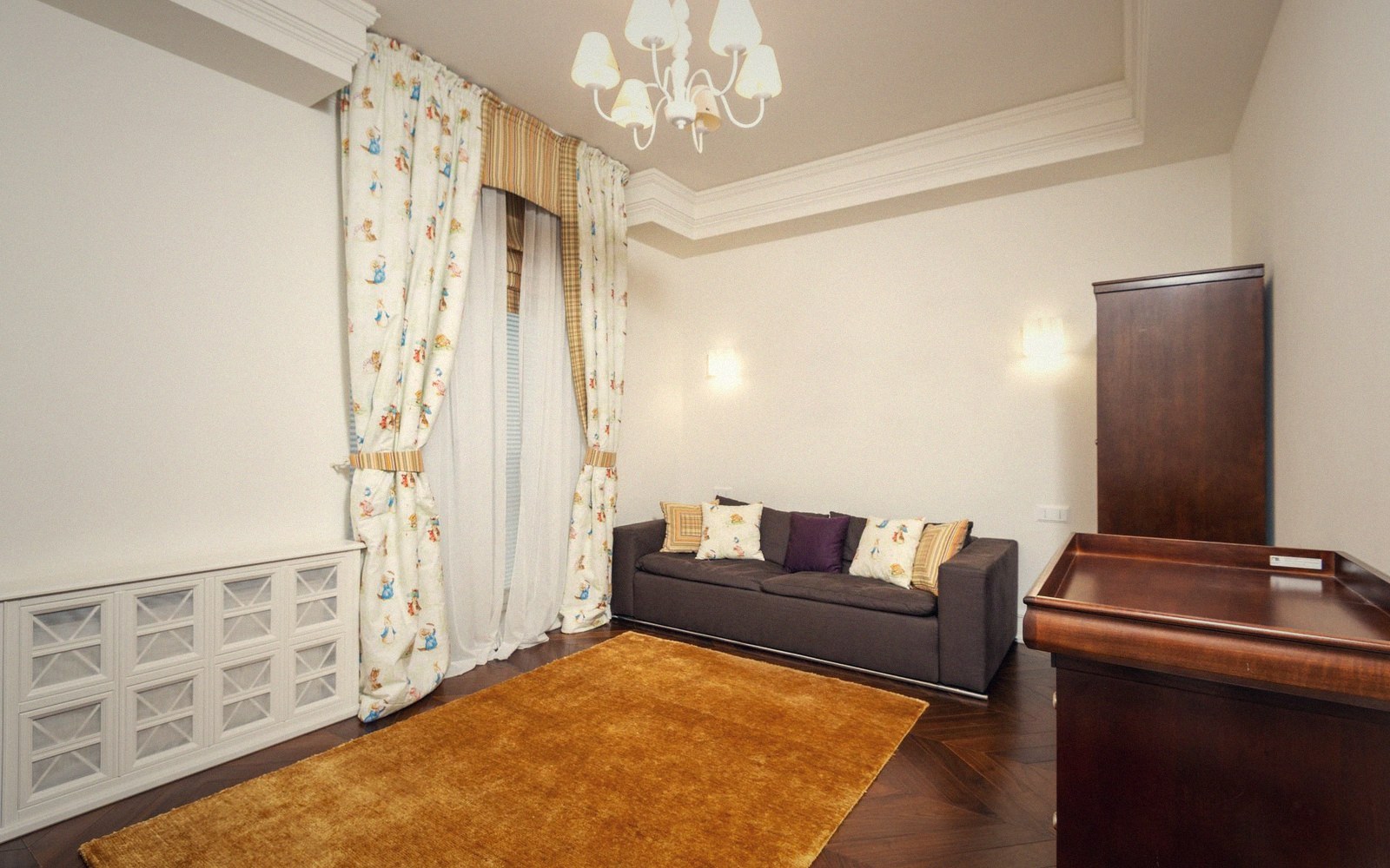 Living room with a brown sofa, patterned curtains, orange rug and wooden furniture
