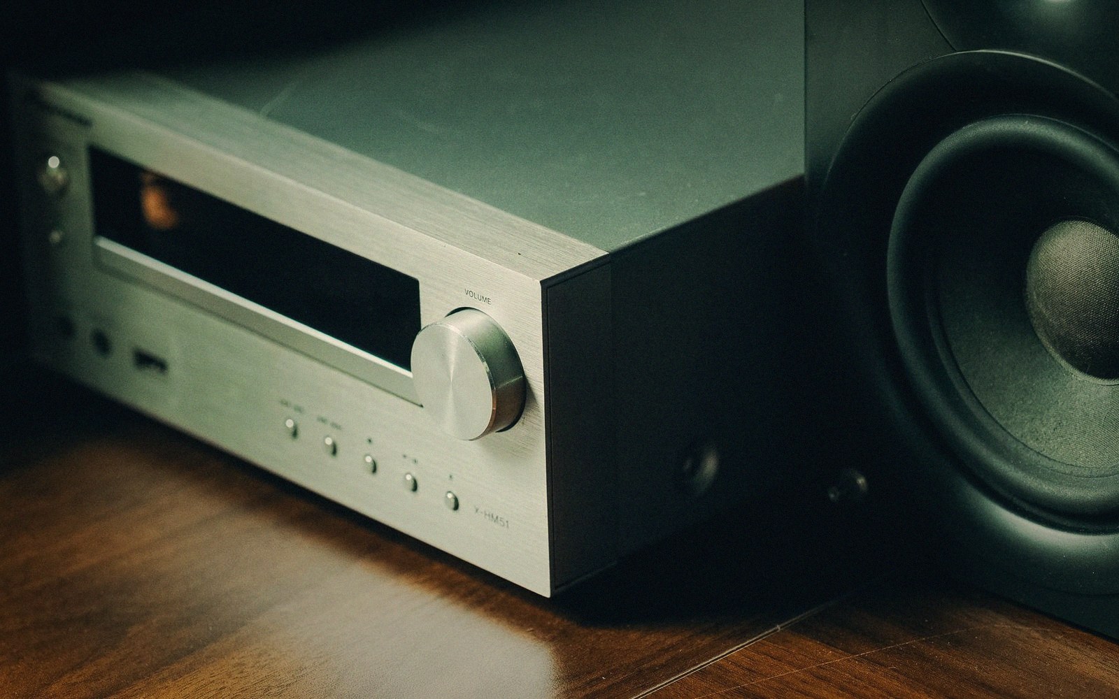 Silver hi-fi receiver with volume knob sitting beside a black speaker